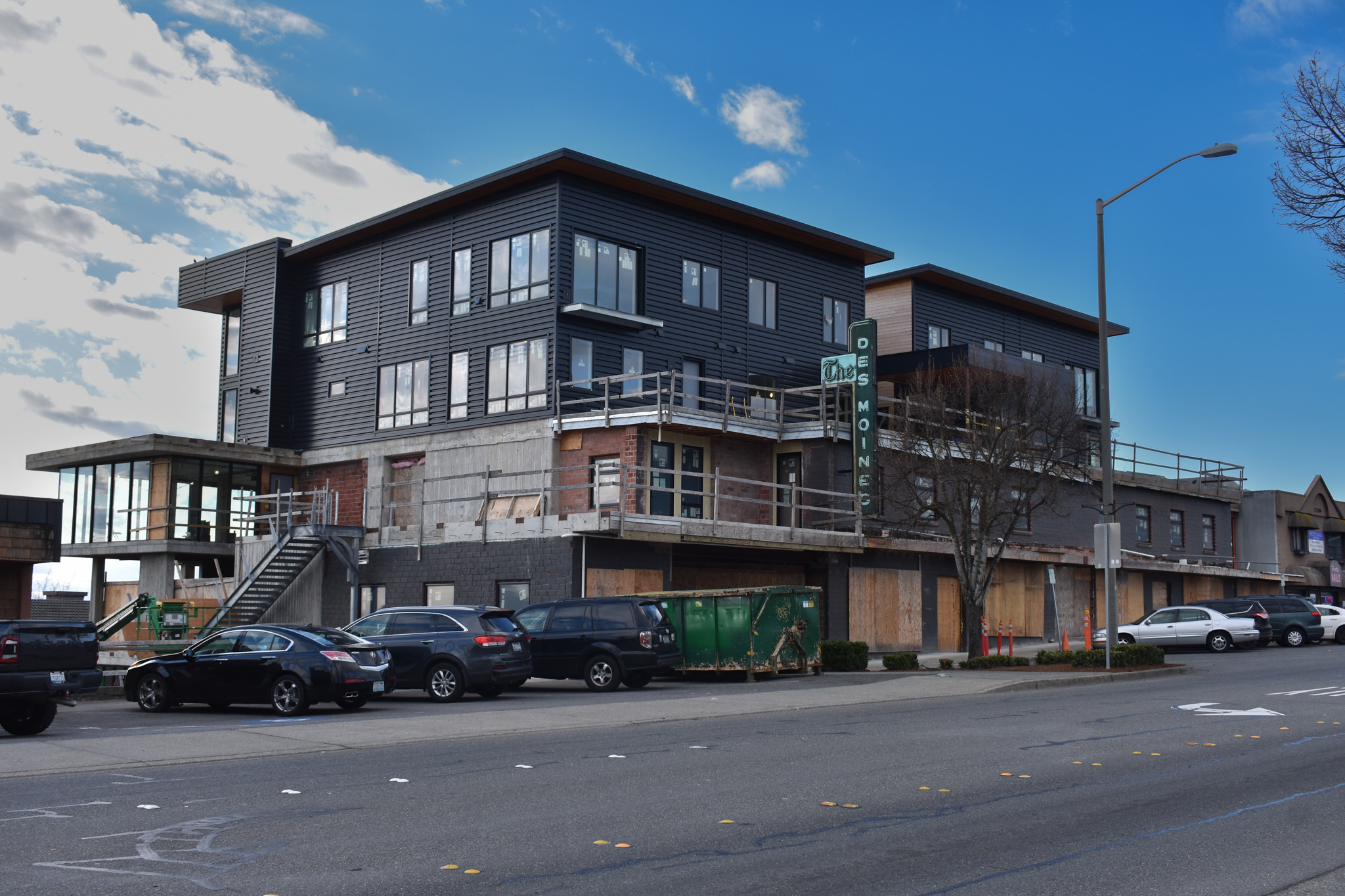 "An image showing unframed aluminum panels stacked in a warehouse or construction shop, with partially built walls in the ...